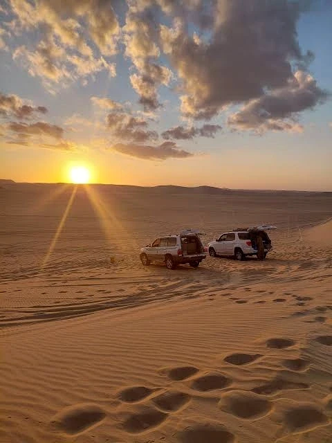 シーワの砂丘と4WD車の向こうに沈む夕日